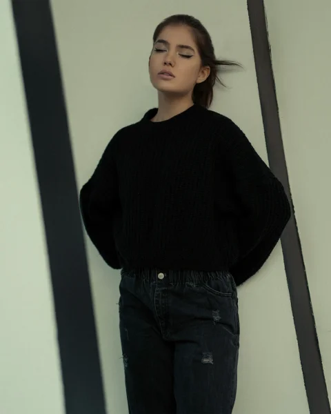 一名穿黑色毛衣的女人靠着墙