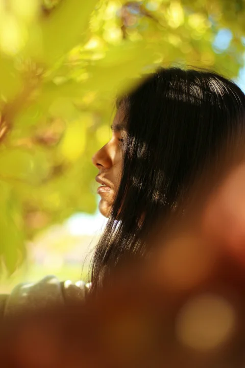 a woman standing under a tree with her eyes closed