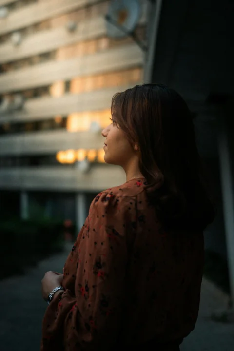 Woman looks towards a building in the fading light