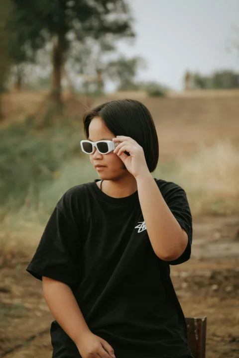 a woman sitting on a bench wearing sunglasses