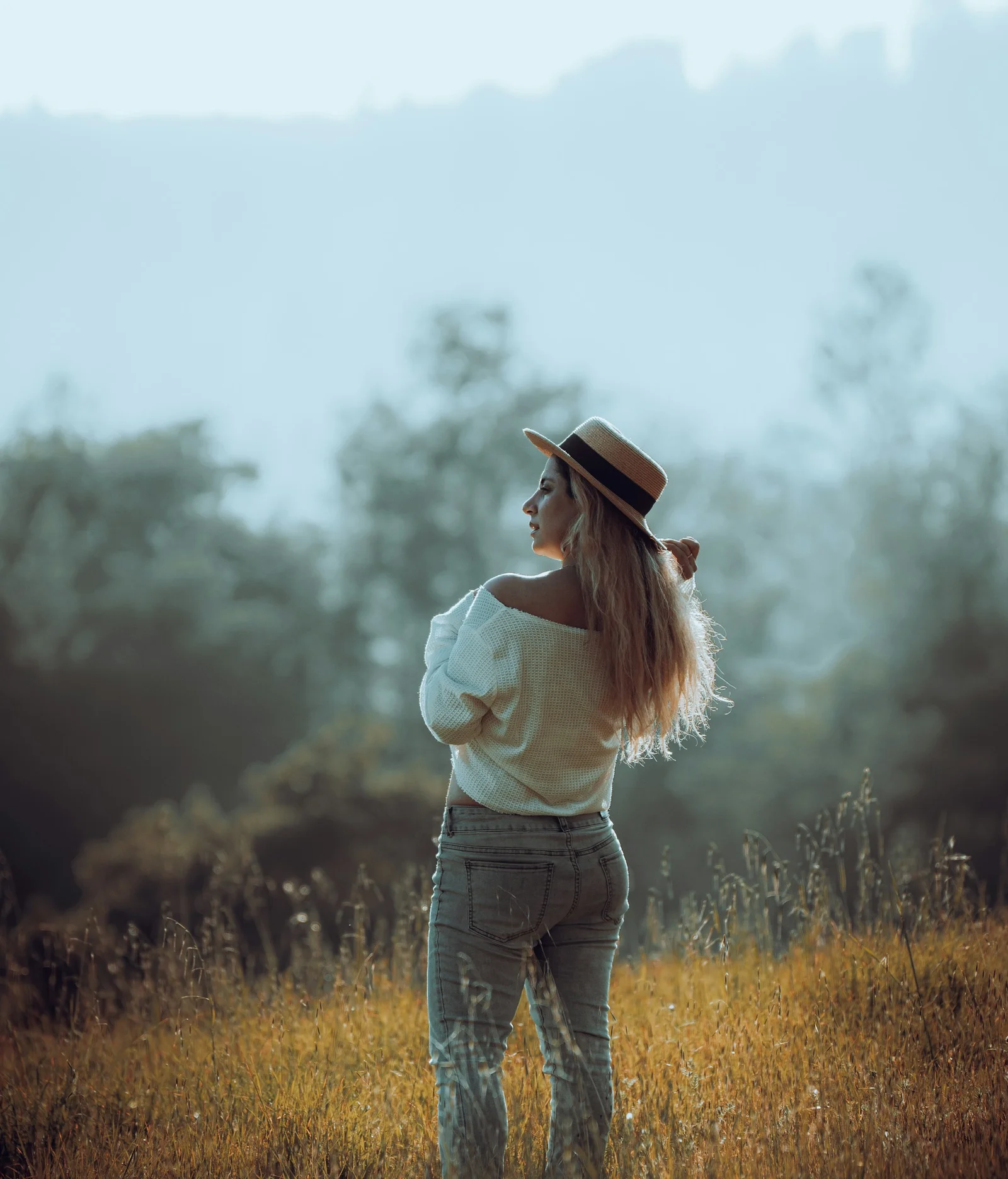 a woman in a hat standing in a field