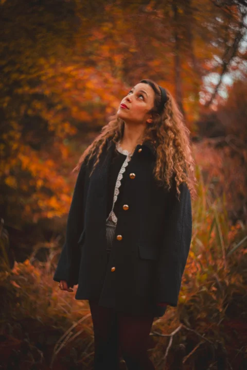 Woman looking up amidst autumn foliage