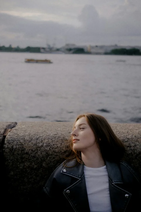 Young woman in leather jacket by the water