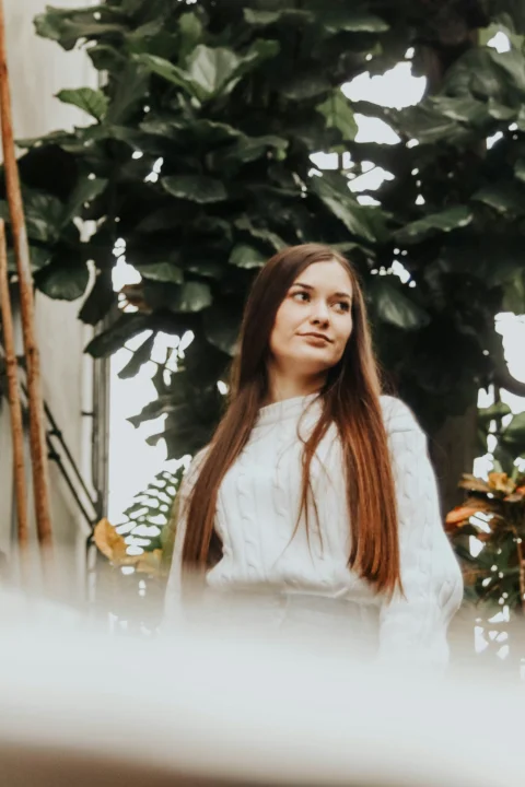 a woman with long hair standing in front of a tree