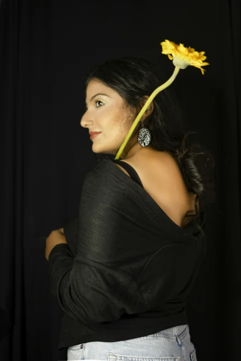 woman in black tank top holding yellow flower