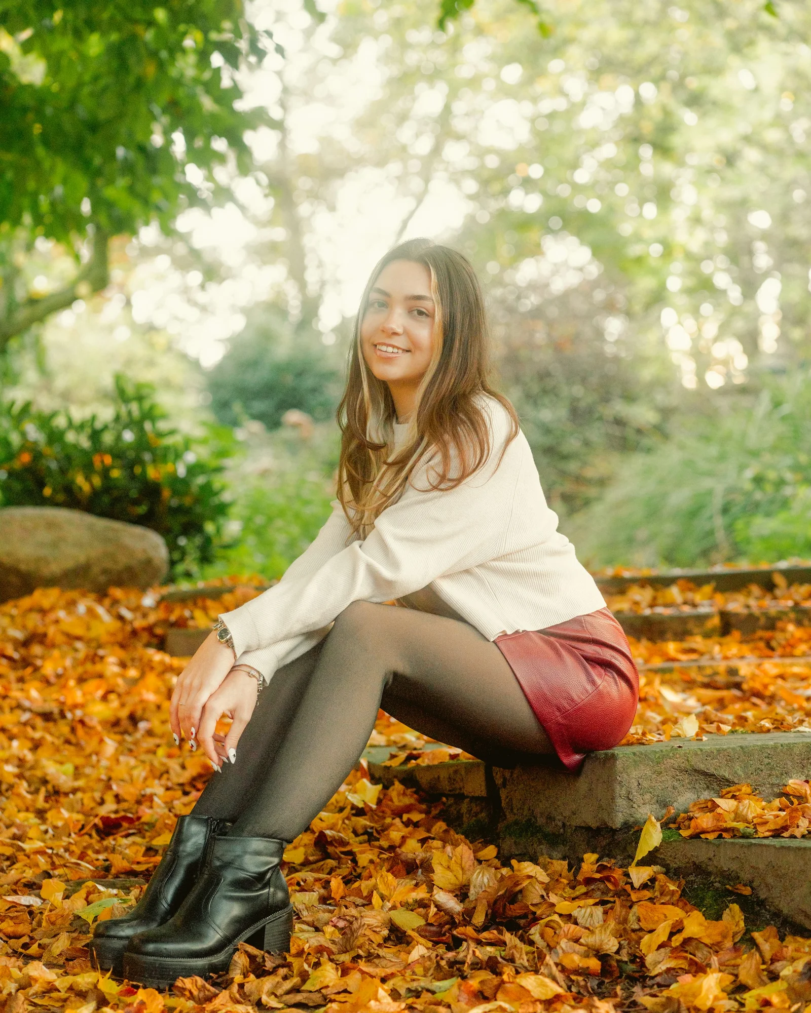 A young woman smiles, sitting on autumn steps