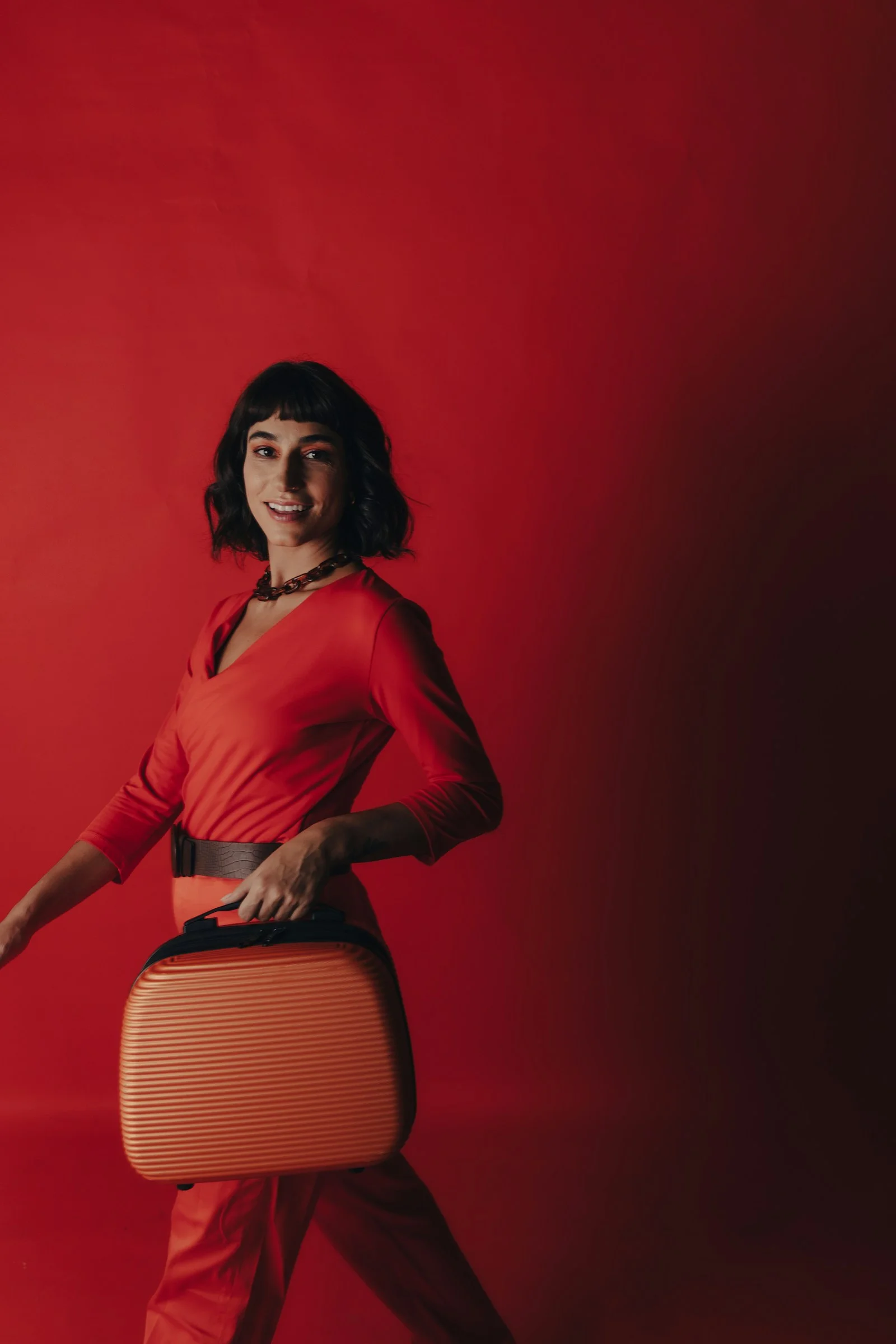 a woman in a red top is holding a suitcase