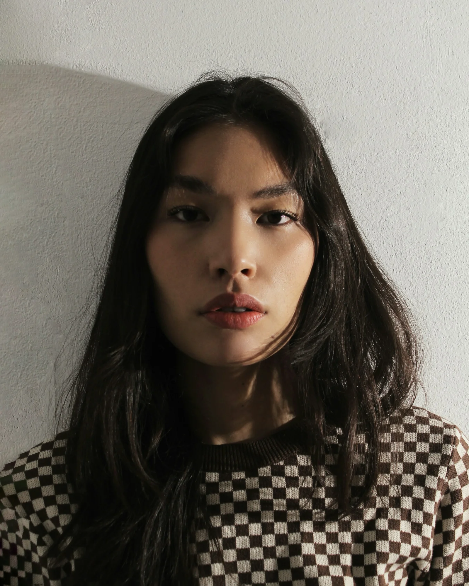 a woman with long hair wearing a checkered sweater