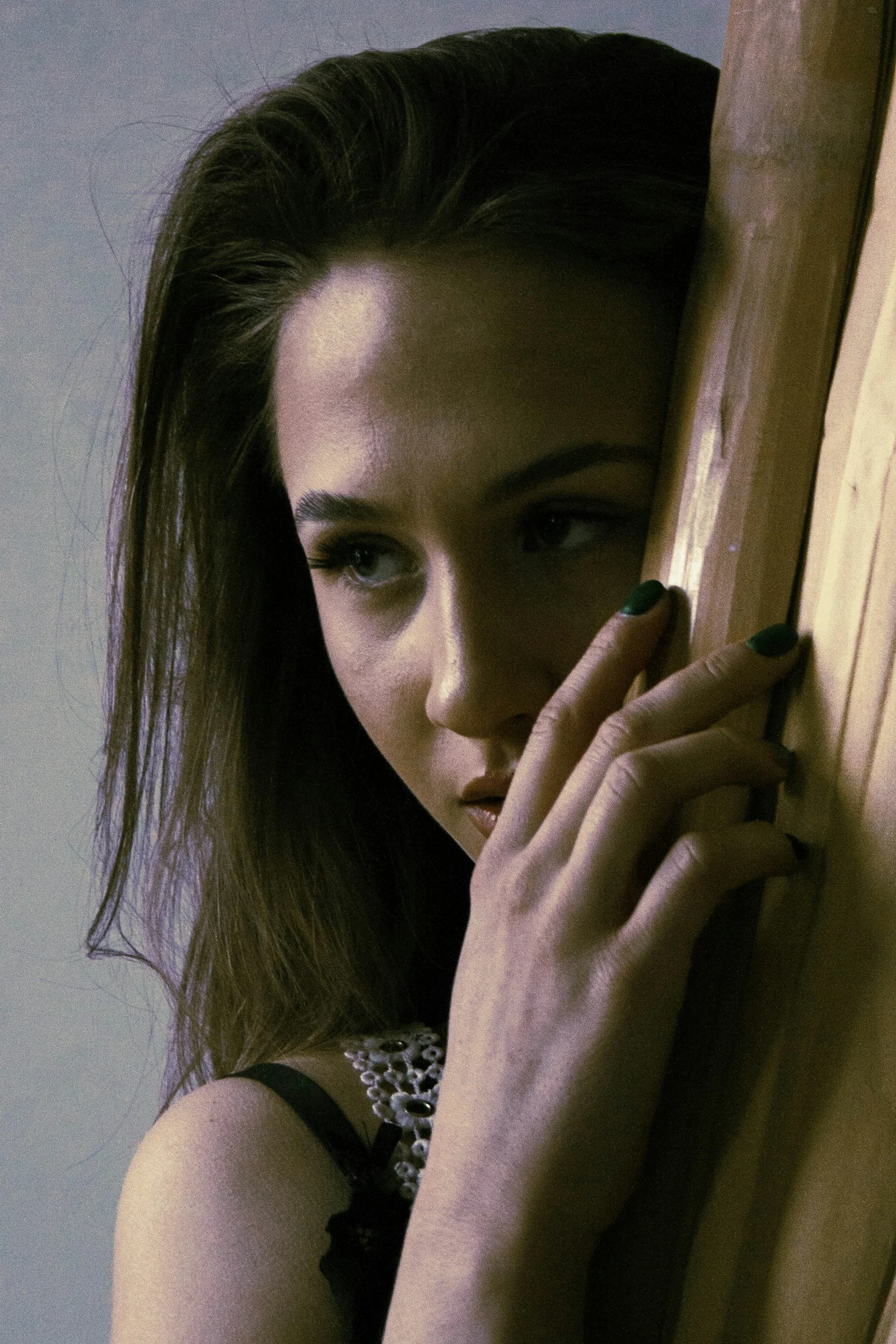 a woman leaning against a wooden wall with her hand on the side of the wall