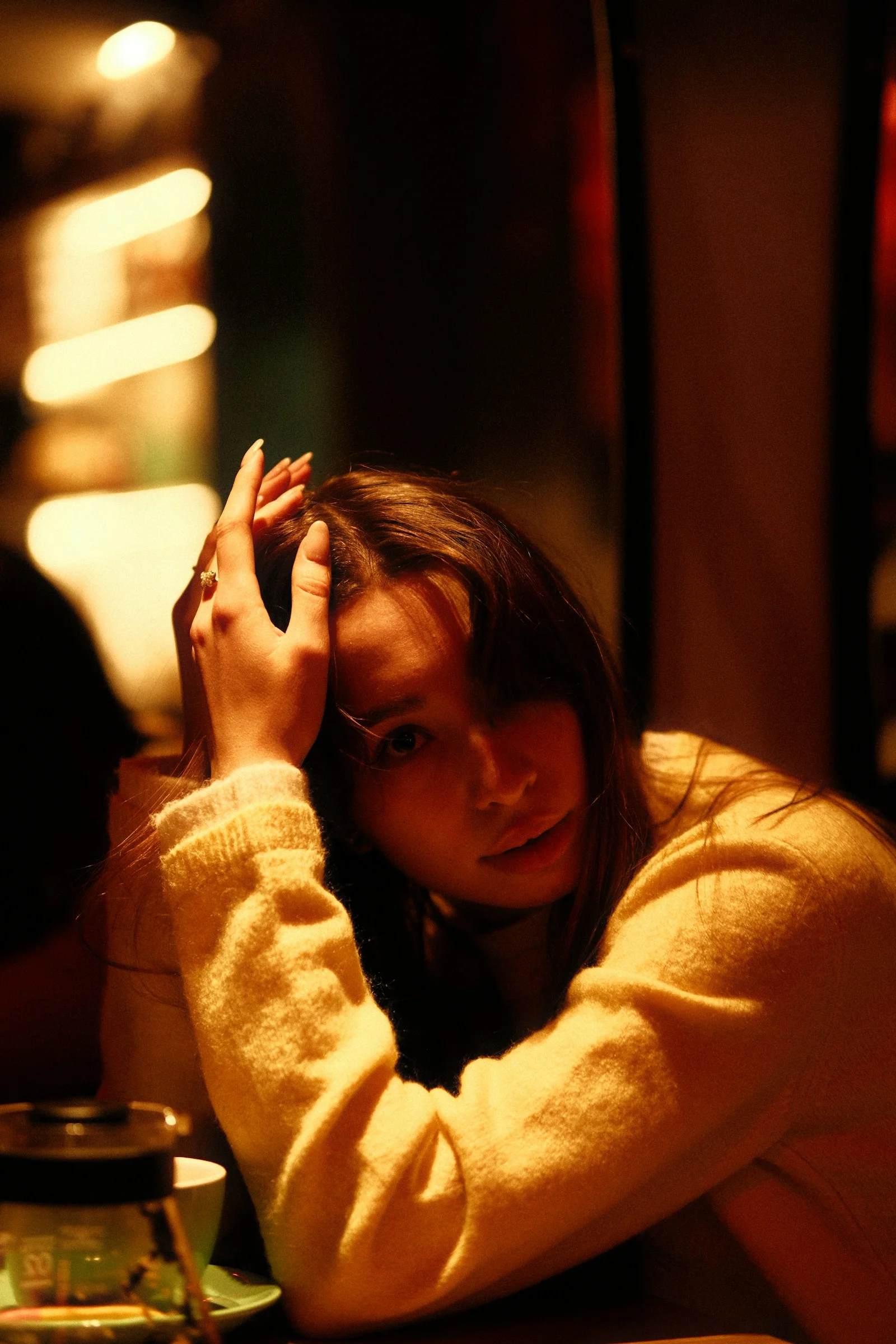 薄暗い光の中で頭に両手を当てた若い女性
