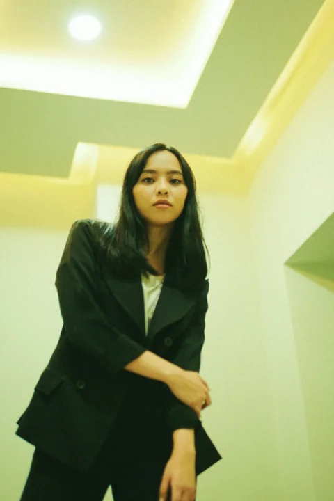 woman in black blazer standing near white wall