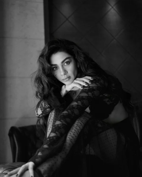 A woman poses elegantly in black lace