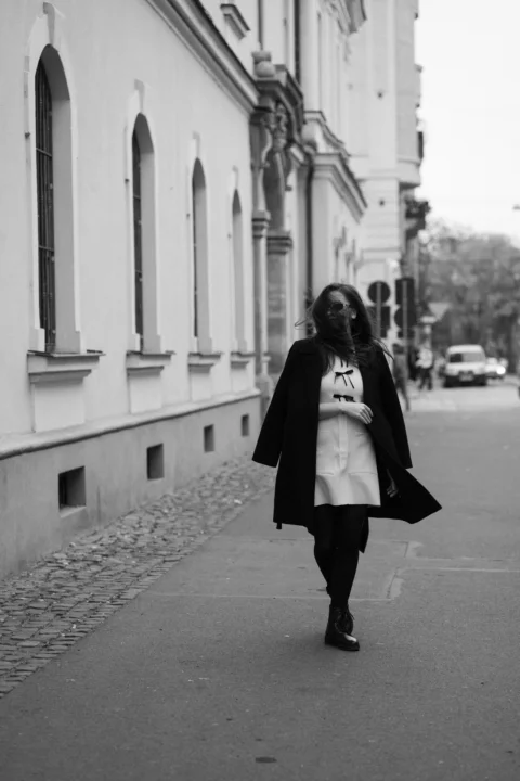 A woman walking down a street next to a tall building