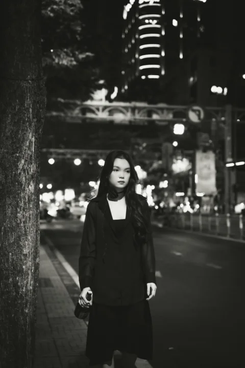 歩道の木のそばに立つ女性