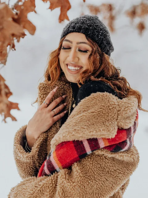 一个穿着夹克戴着帽子站在雪中的女人