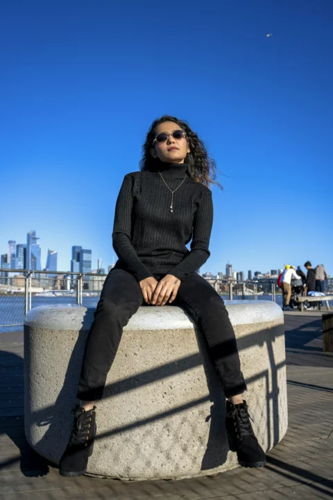 a woman sitting on top of a cement pillar