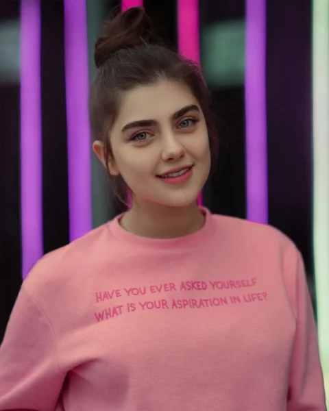 a woman in a pink shirt is smiling