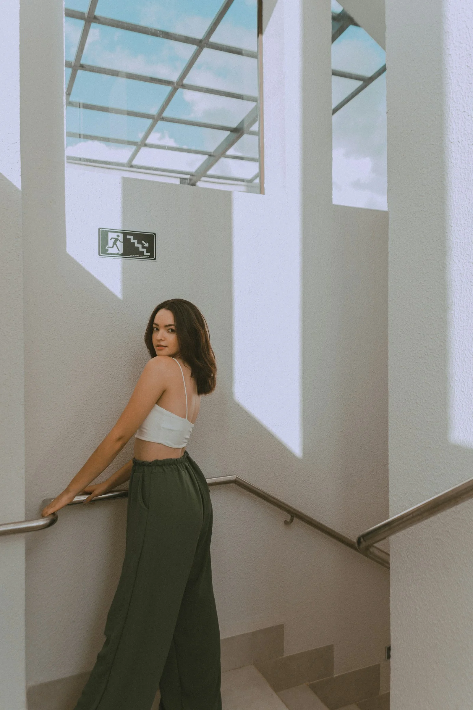 a woman in a white top and green pants