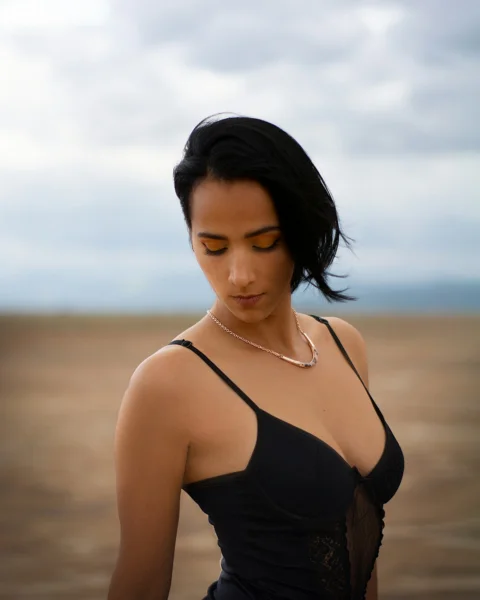a woman in a black dress looking down at her cell phone