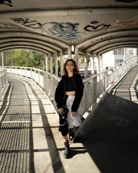 a woman standing on a bridge with a skateboard
