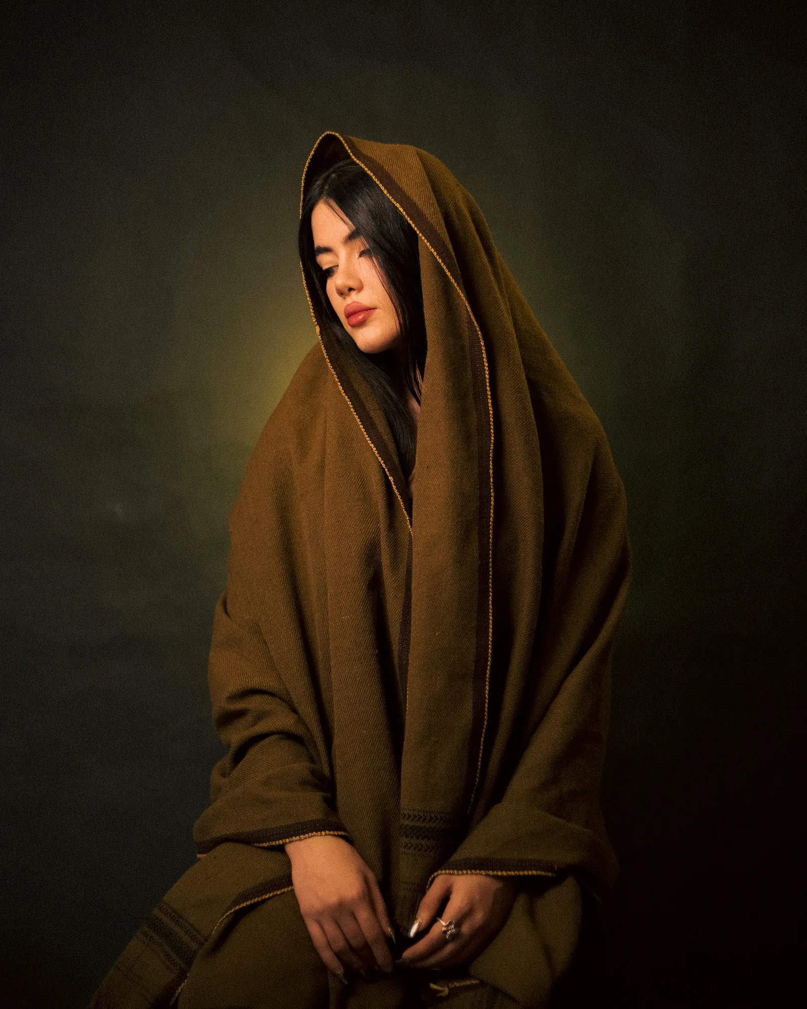 A woman in a brown robe sitting on a stool