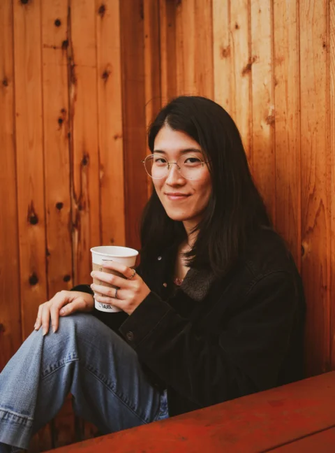 一位坐在长椅上手拿咖啡杯的女士