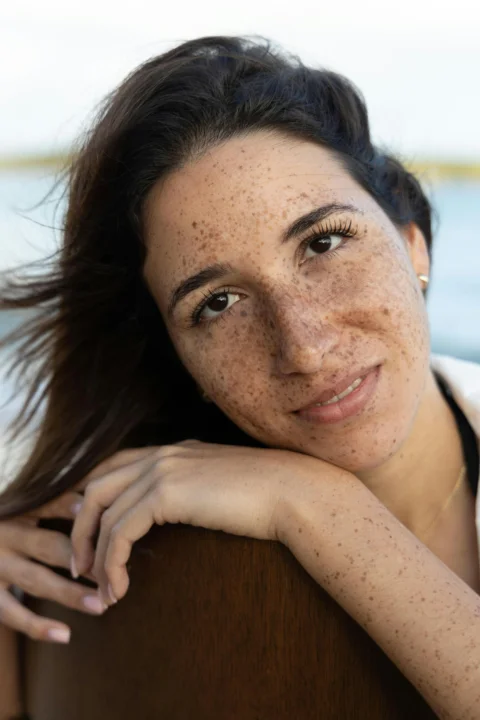 Smiling woman with freckles leaning on a wooden surface