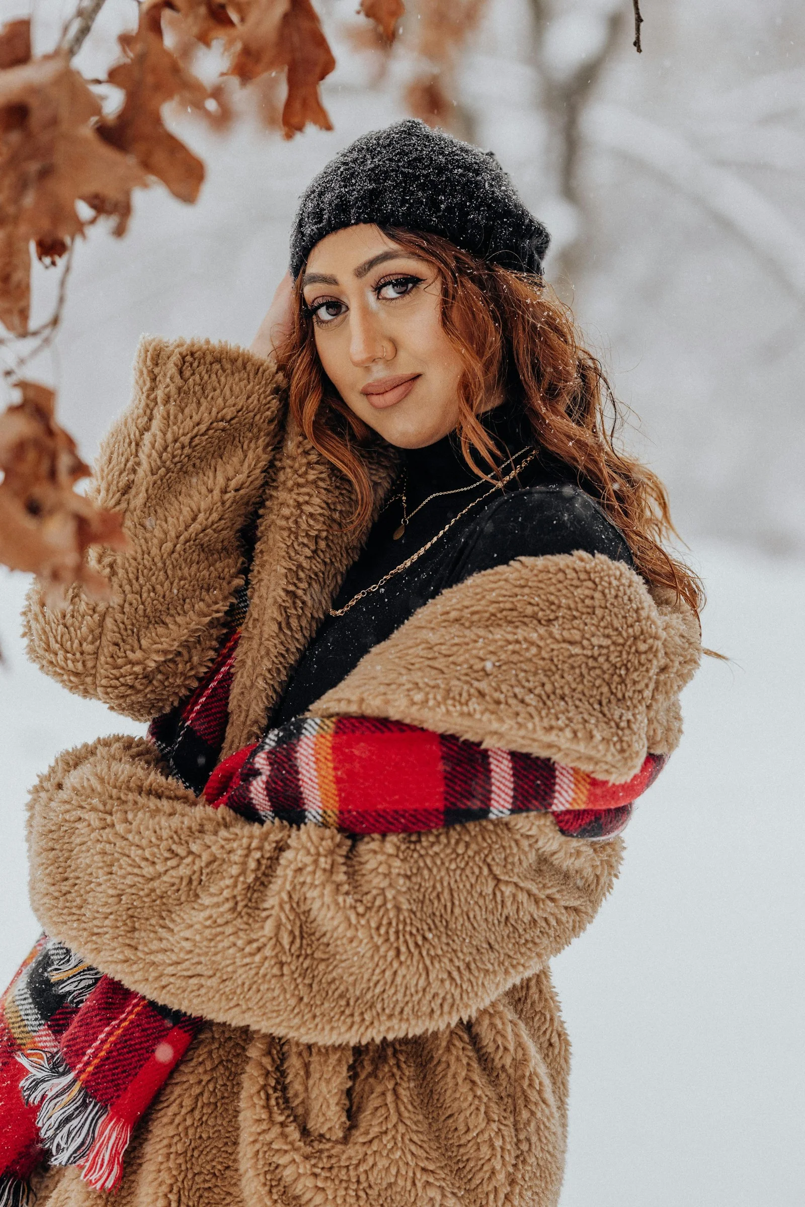 一位女子站在雪中，双臂环抱头部