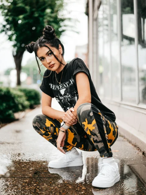 a woman kneeling down on a wet sidewalk