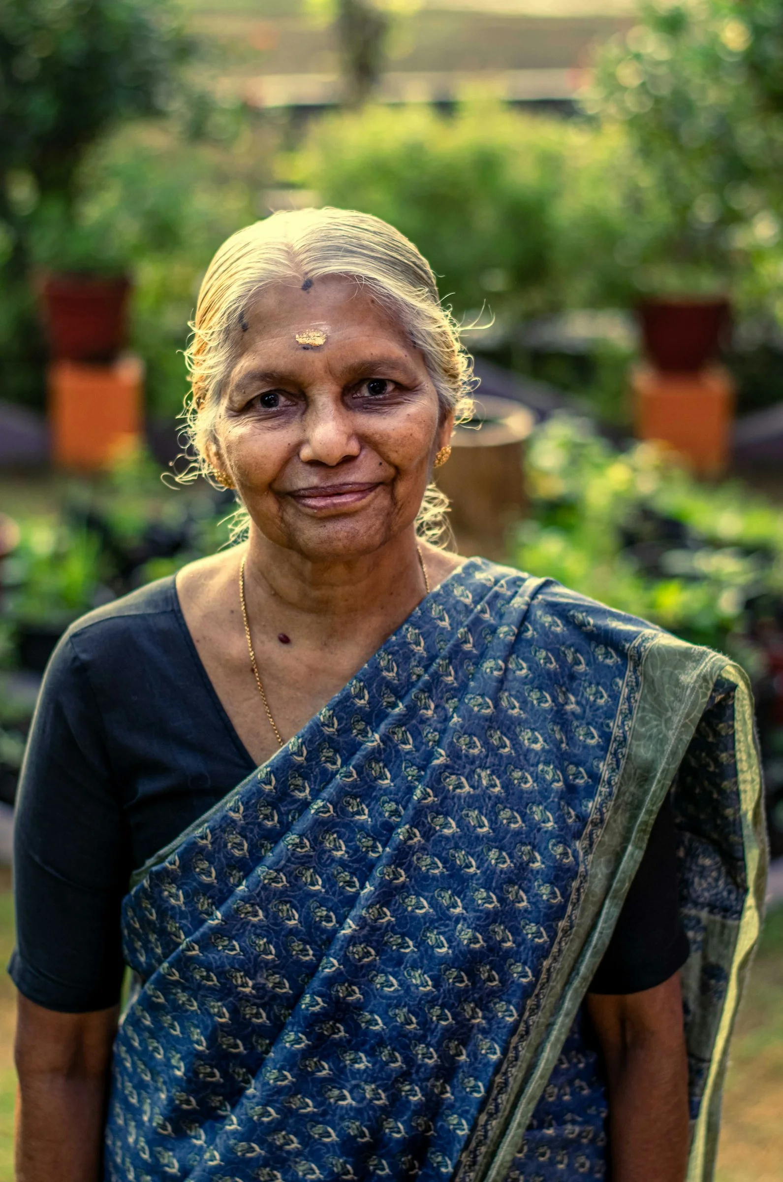 a woman in a blue sari standing in a garden