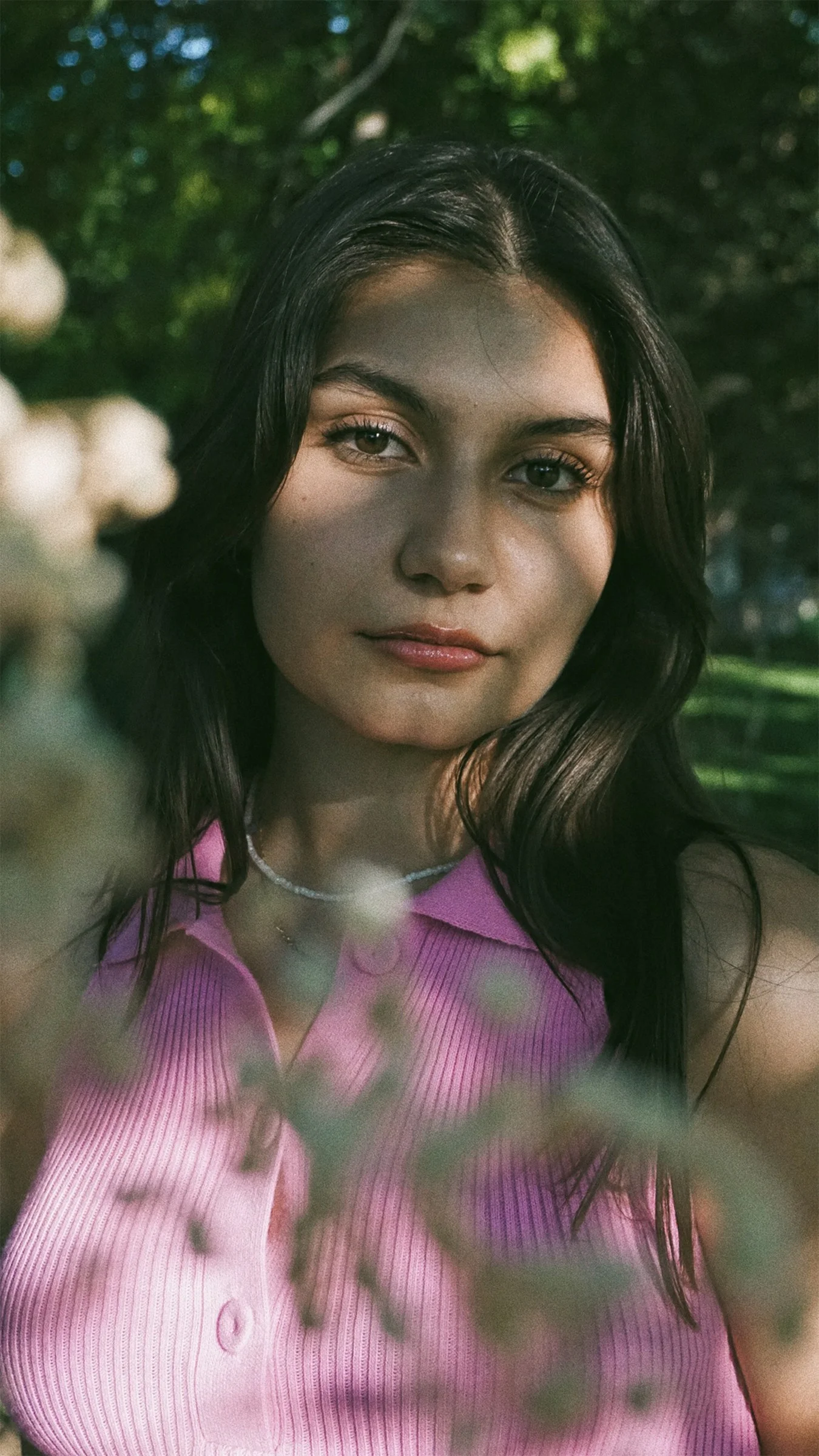 一位穿粉色襯衫的女性正擺姿勢拍照