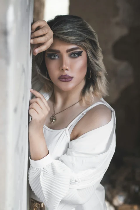 a woman in a white top leaning against a wall