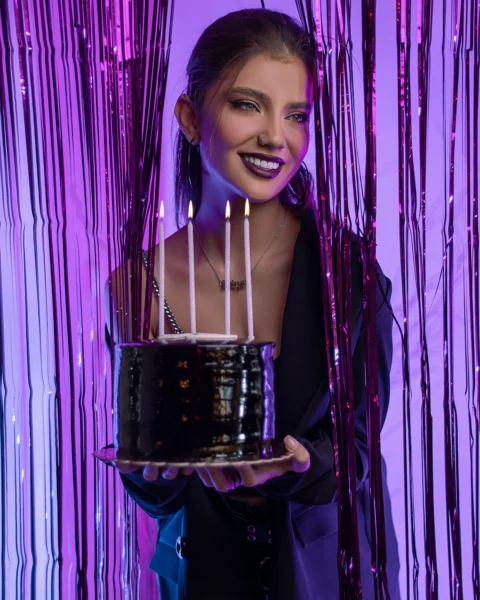 一位捧着点着蜡烛的蛋糕的女人