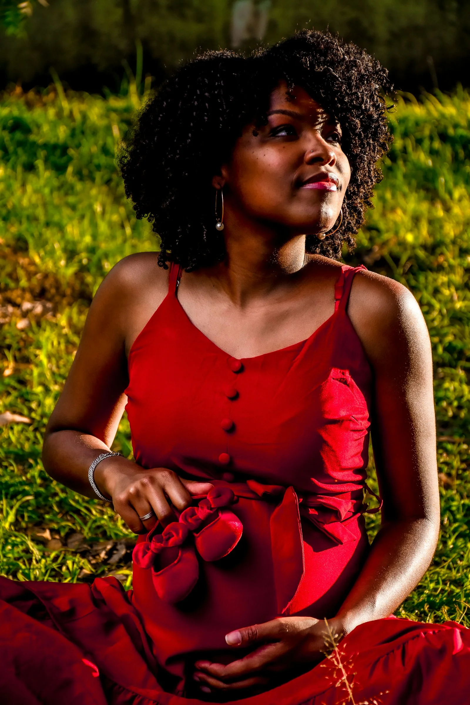 a woman in a red dress sitting on the grass