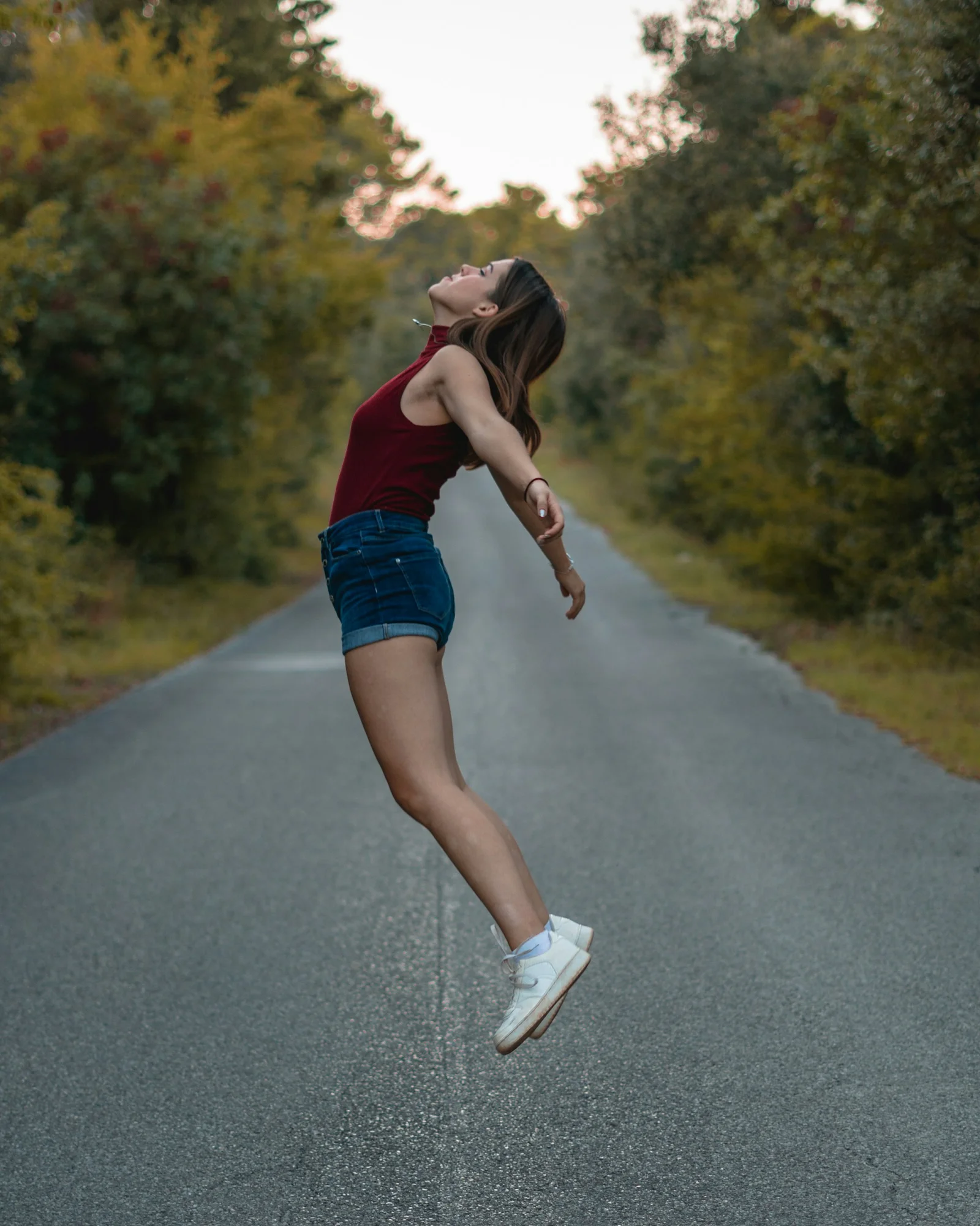 a woman jumping in the air on a road