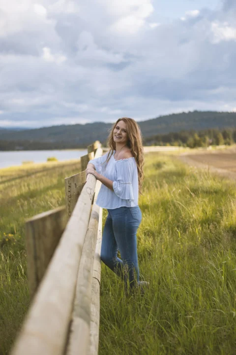 a woman standing on a wooden fence