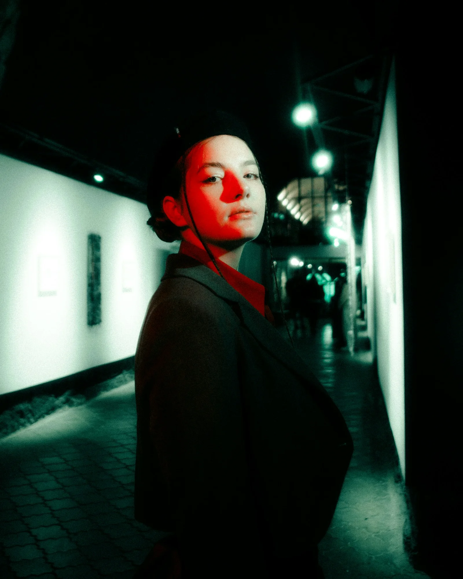 A woman standing in a hallway with a red light on her face