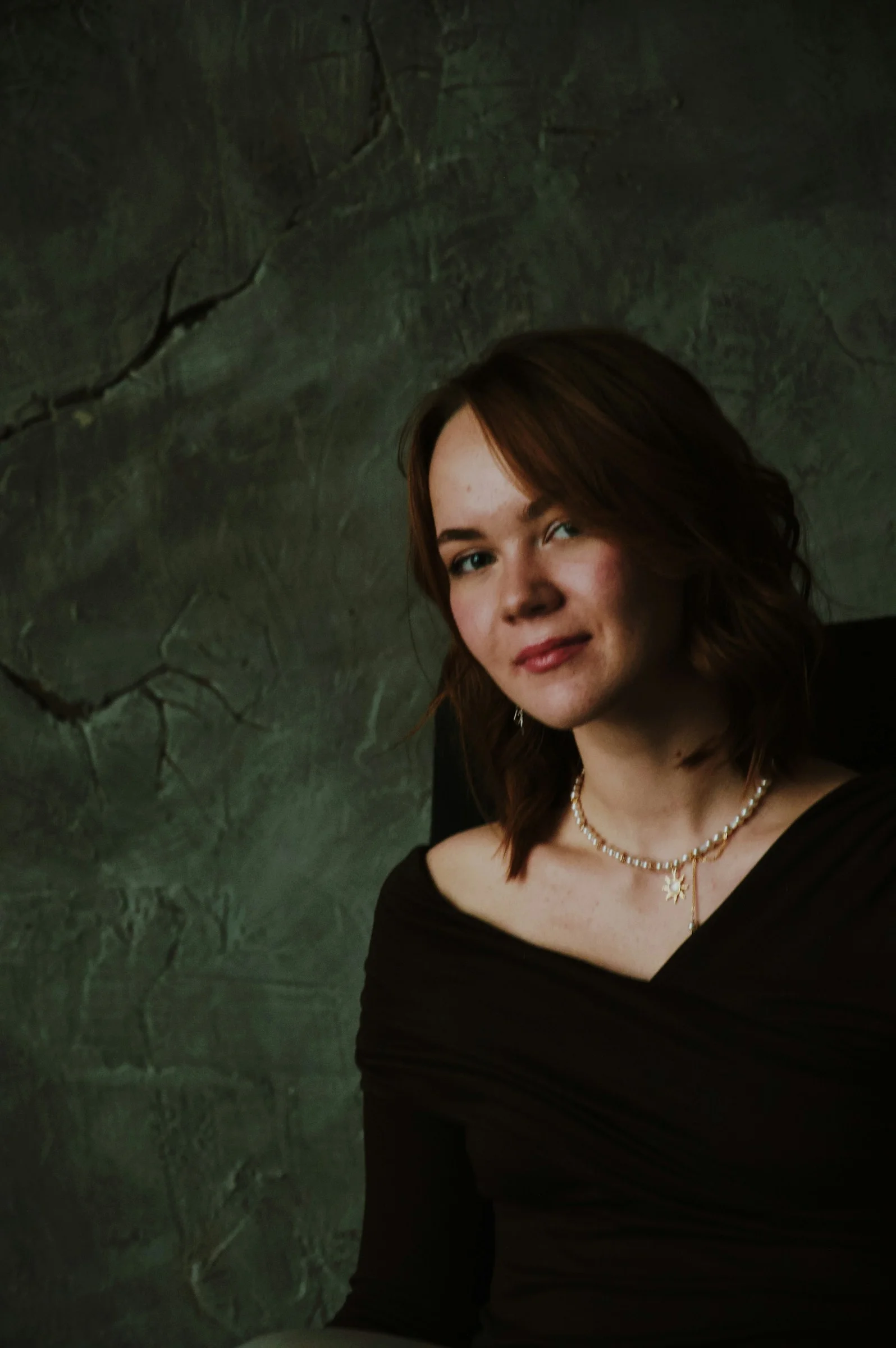 Young woman with short brown hair and pearl necklace