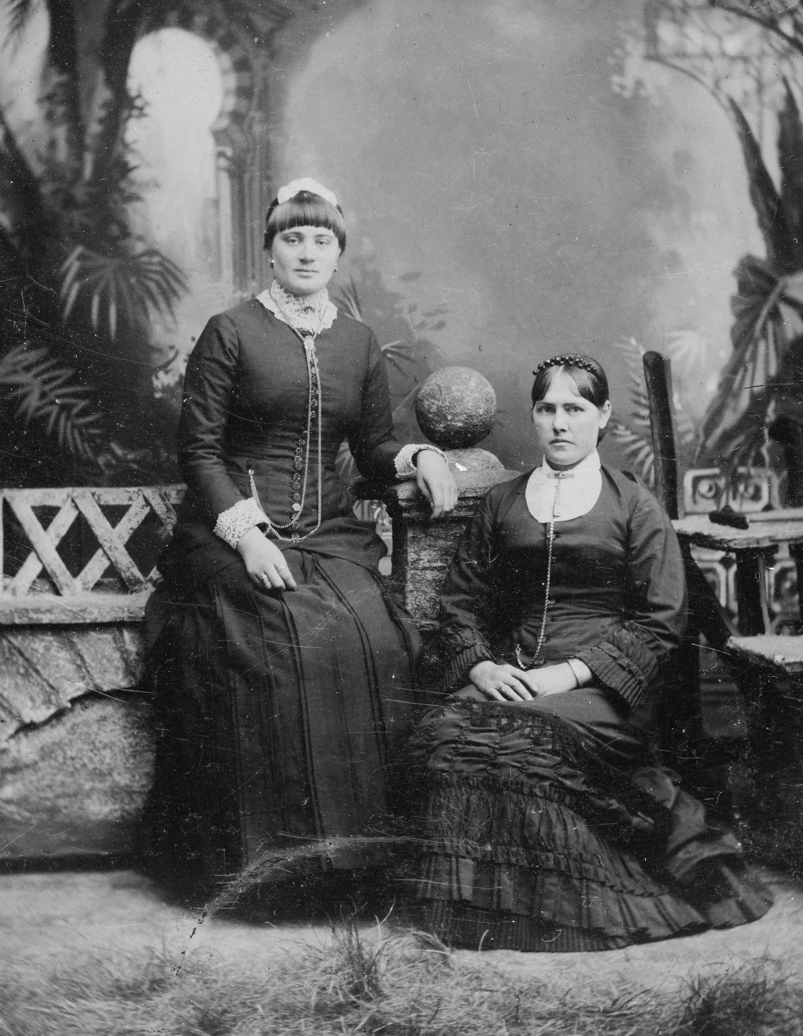 Two women in victorian dresses posing for a studio portrait
