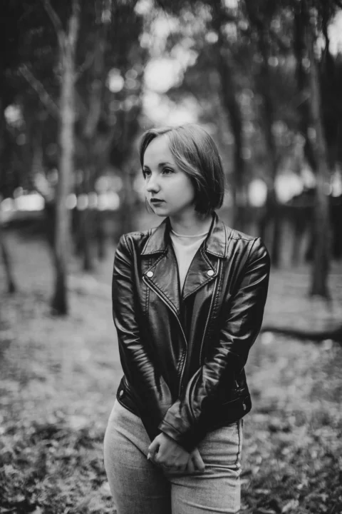 Young woman in leather jacket standing in forest