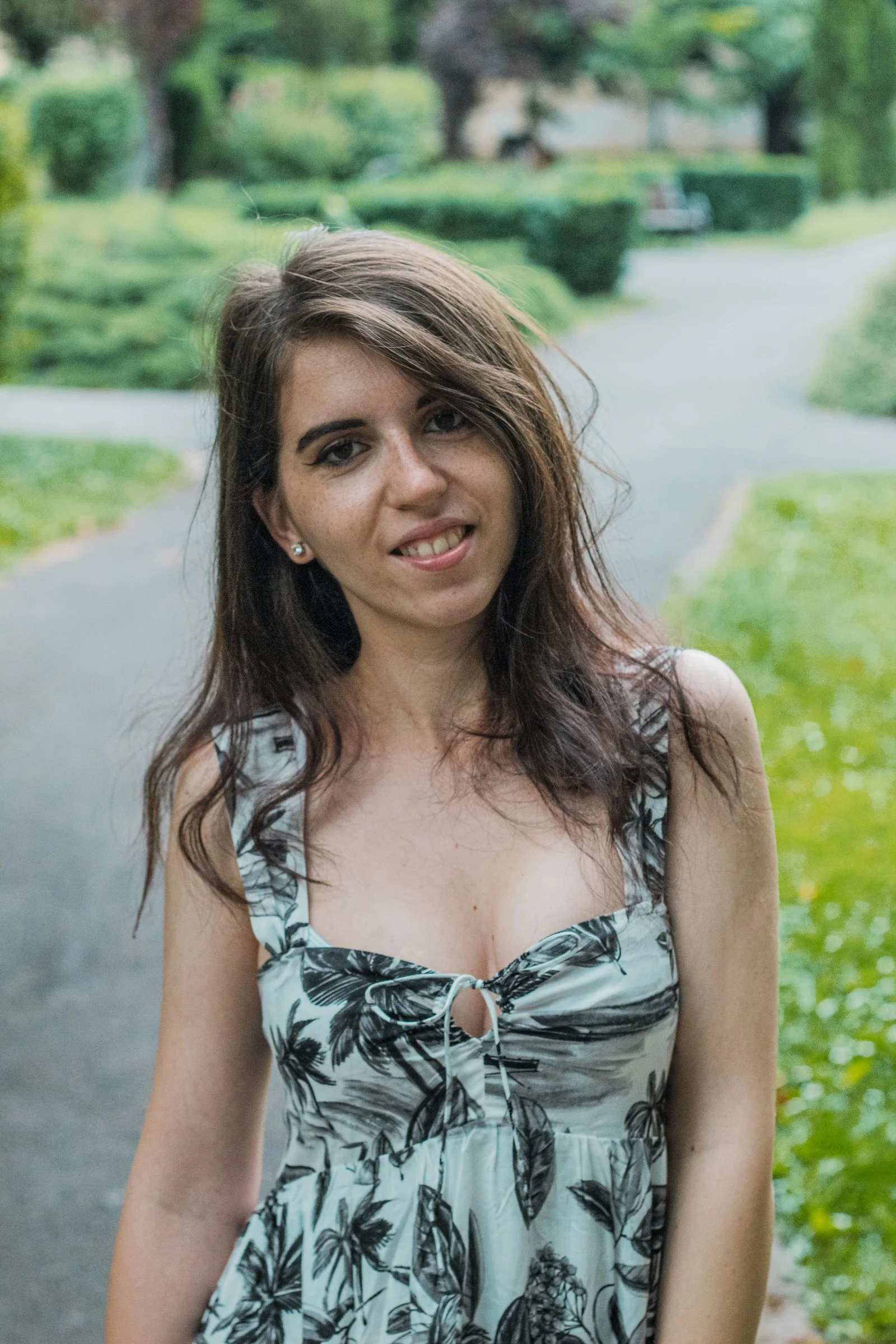 青と白の花柄キャミソールトップスを着て微笑む女性