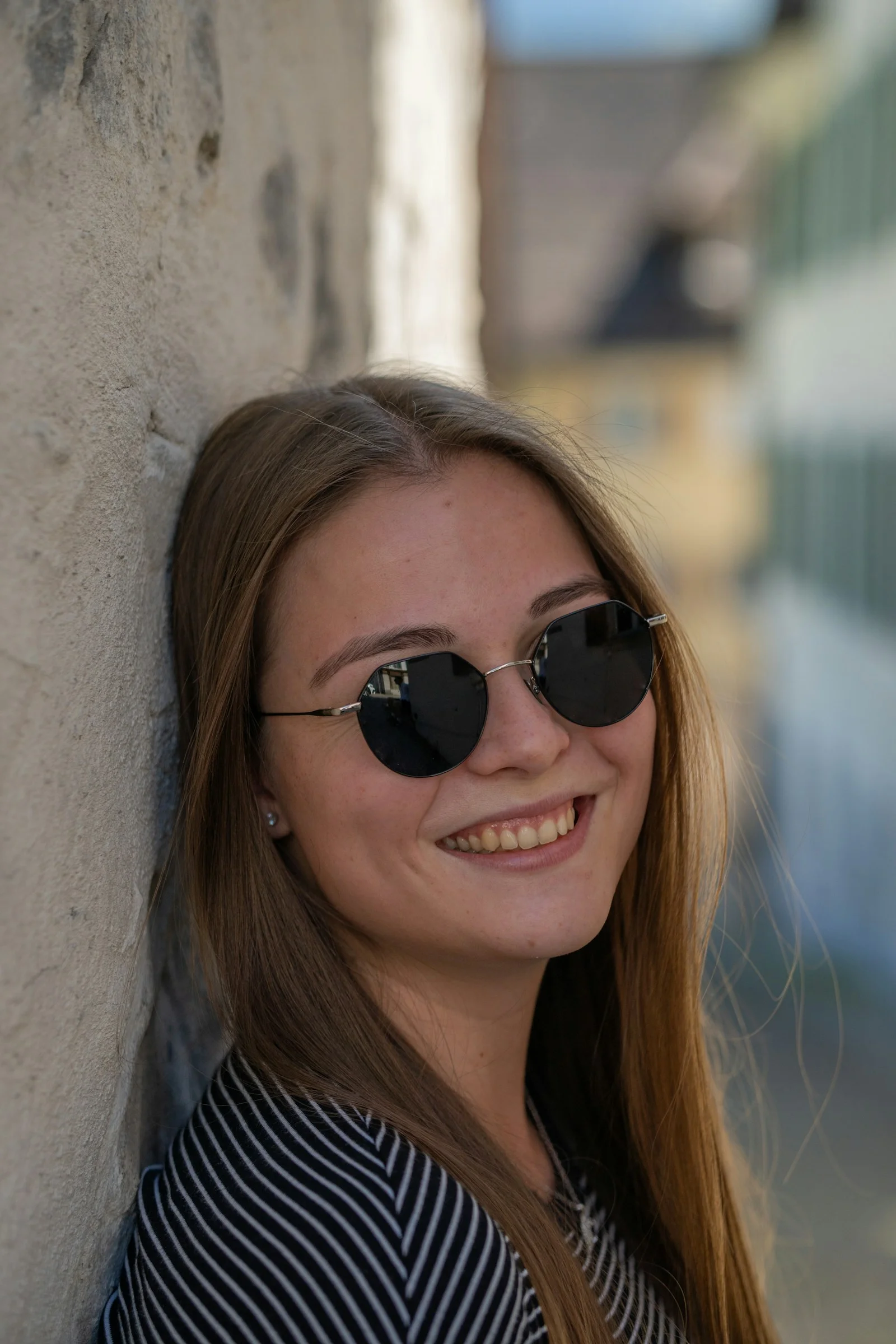 A woman wearing sunglasses leaning against a wall