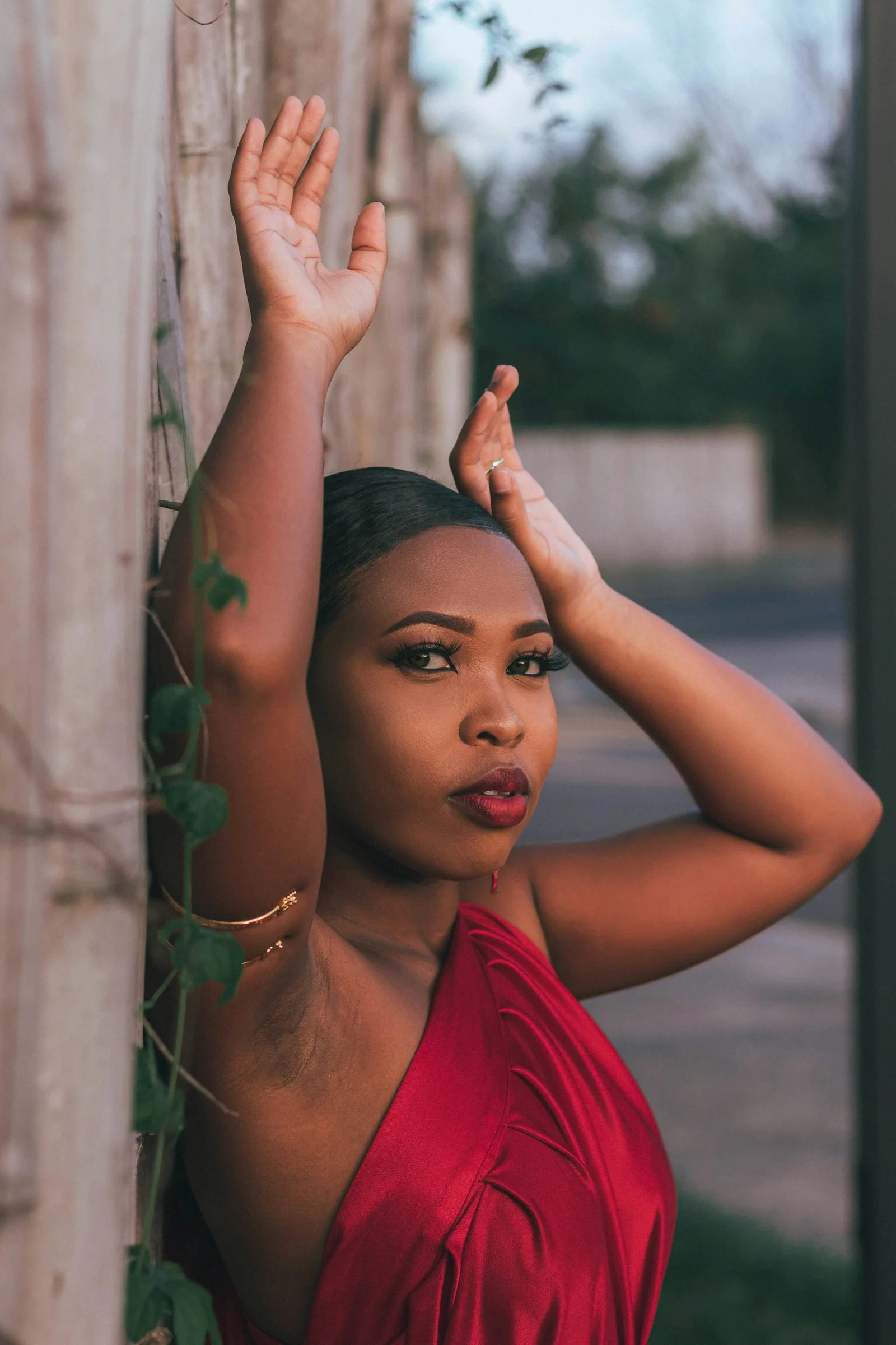 a woman in a red dress leaning against a wall