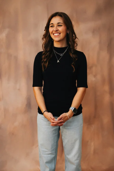 A woman smiles happily in front of a backdrop
