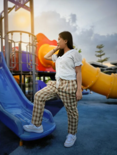 girl in white shirt and white and black pants standing on blue inflatable slide during daytime