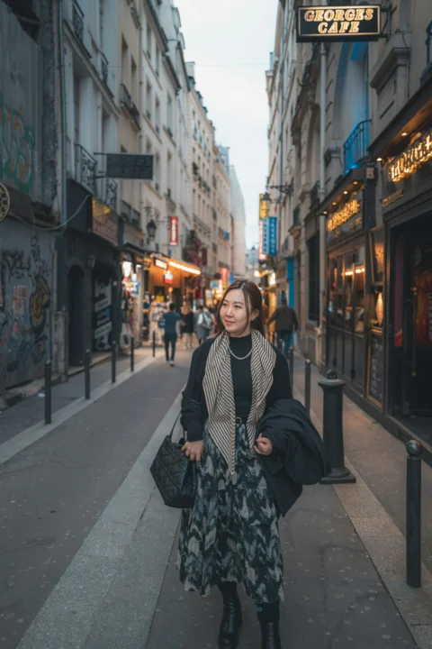 A woman walking down a street next to tall buildings
