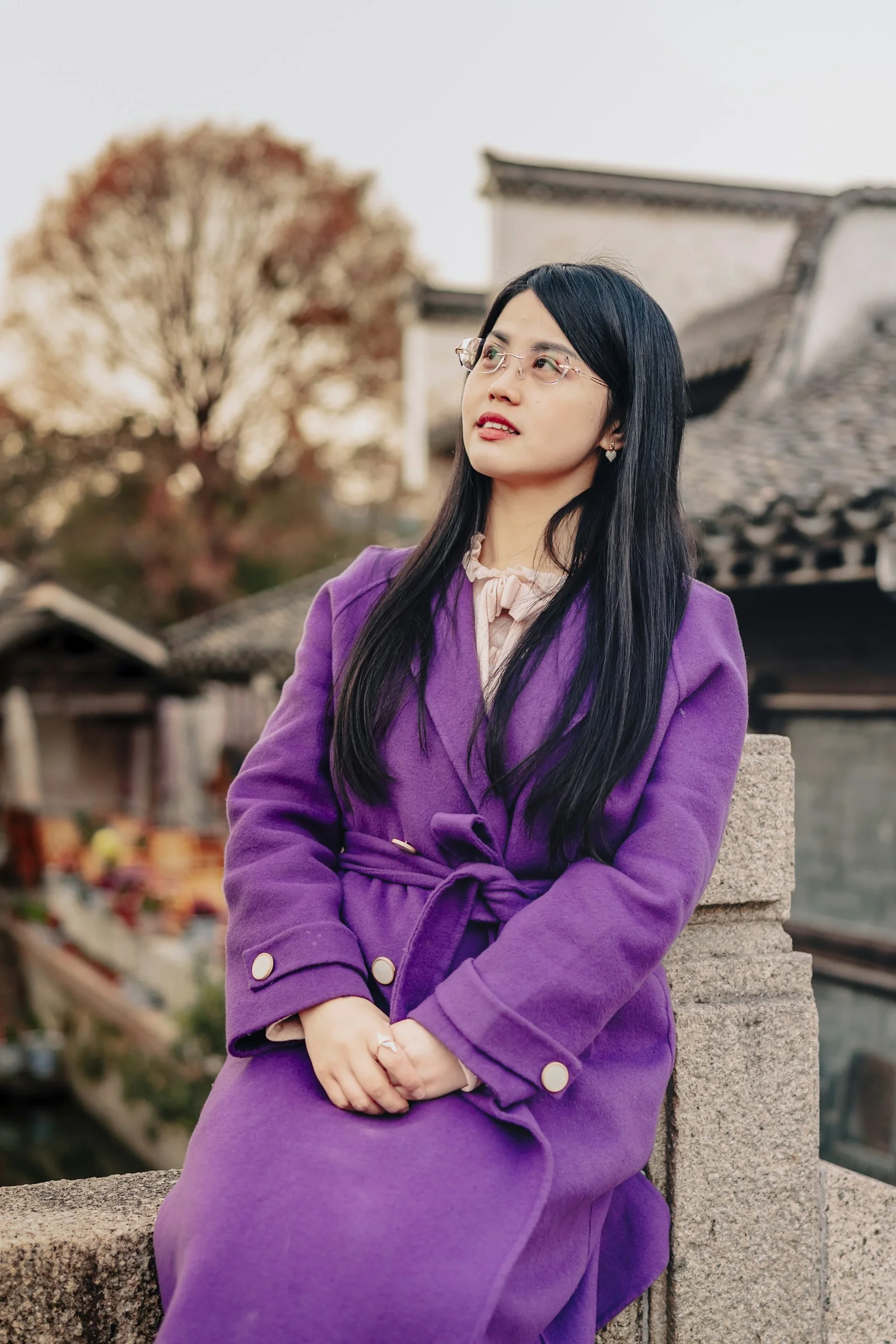 一个穿紫色外套坐在墙上的女人