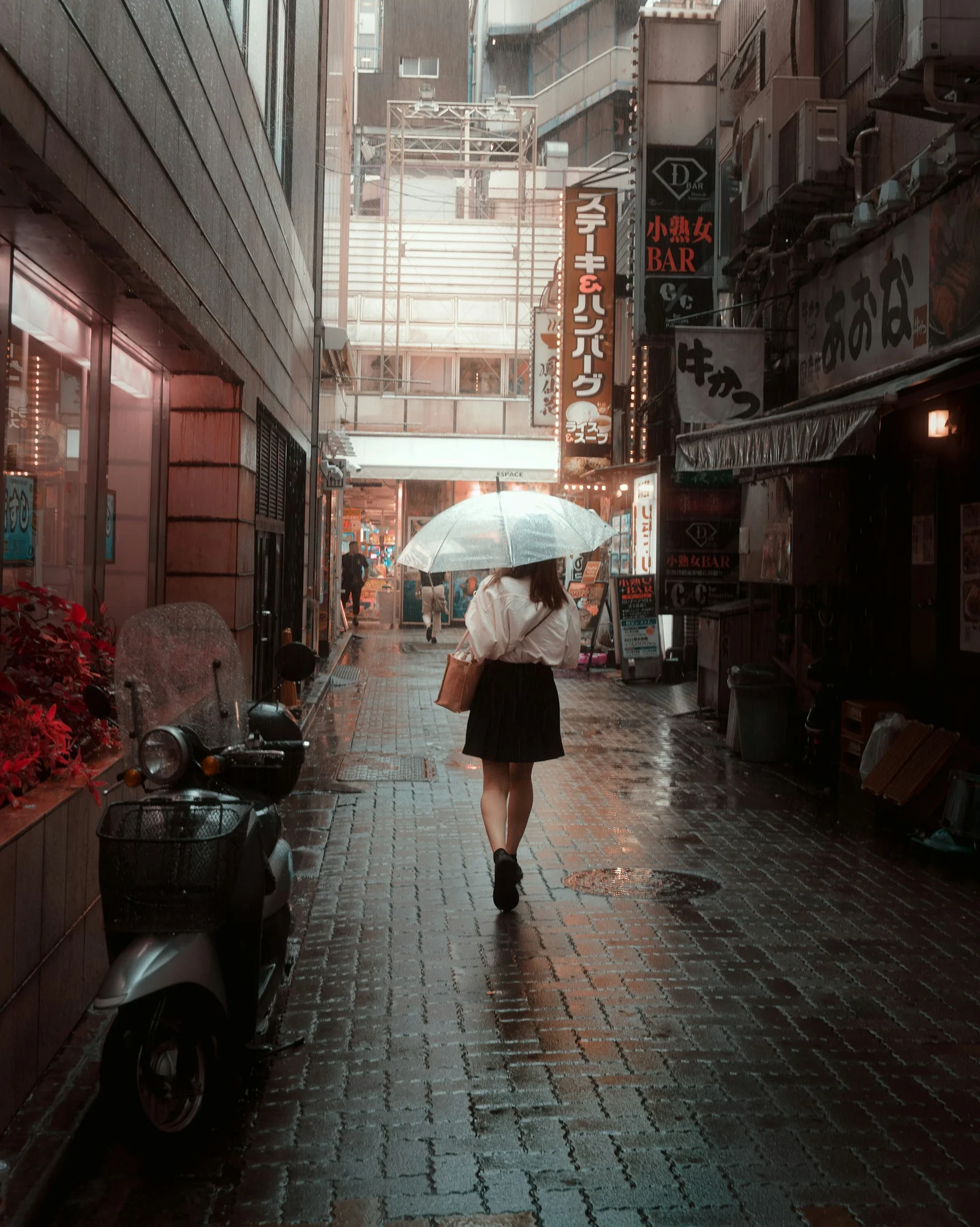 撐傘的女人走在下雨的城市街道上