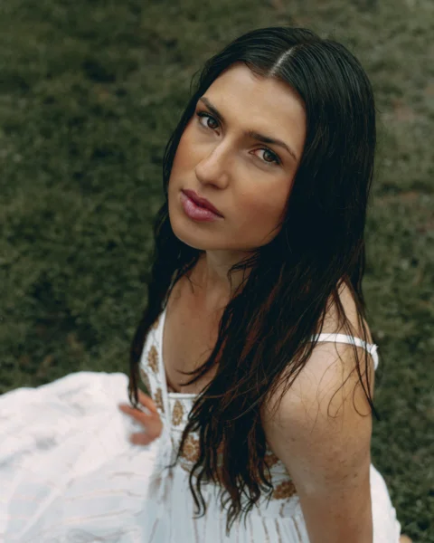 Beautiful woman poses outdoors in a white dress