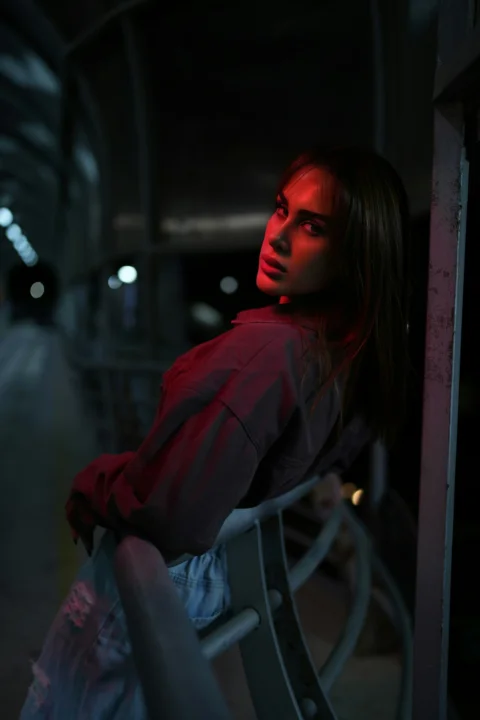 Woman illuminated by red light in a dark setting